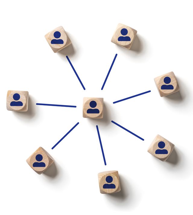 Wooden blocks printed with person icons, arranged in a ring and joined by lines like a professional network, representing the Networking Navigator guidebook.