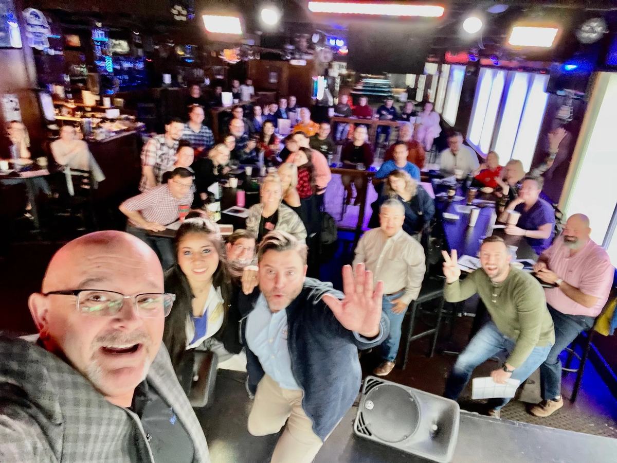 Coach Matt Kern taking a selfie in front of a large, waving crowd at a Denton Square Networkers evening networking event.
